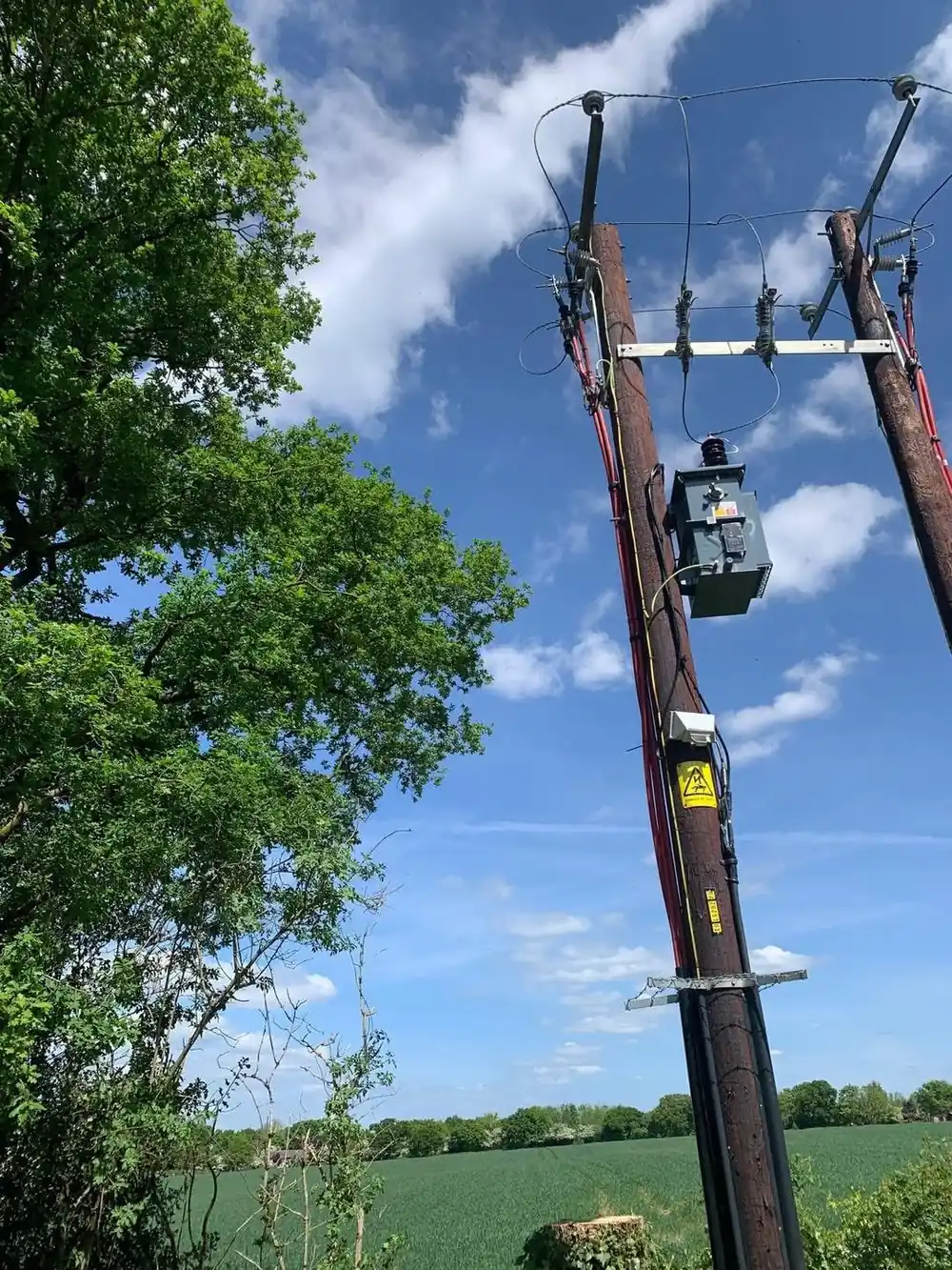 The same transformer with the trees cut back, clear sky around the poles