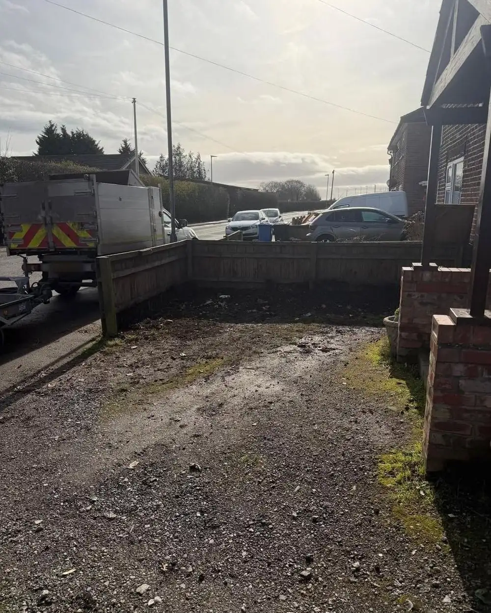The same strip with the hedge removed and the stumps ground out, bare soil ready for a new driveway