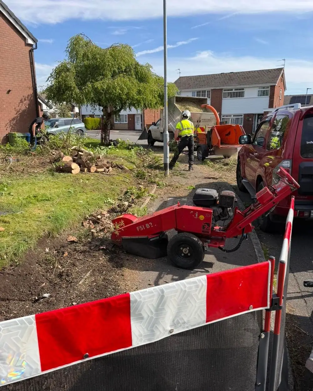 The stump grinder on a cleared verge in St Helens behind a red and white barrier